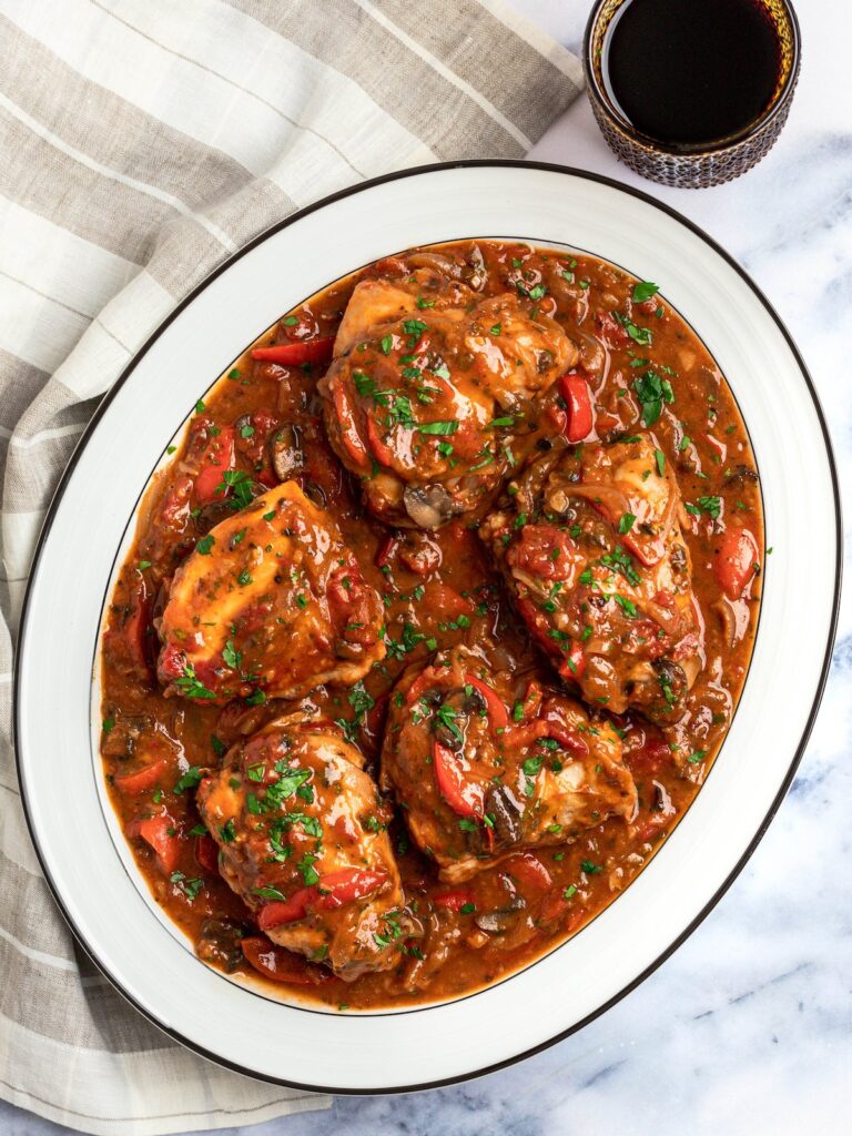 chicken cacciatore on a platter with glass of wine.