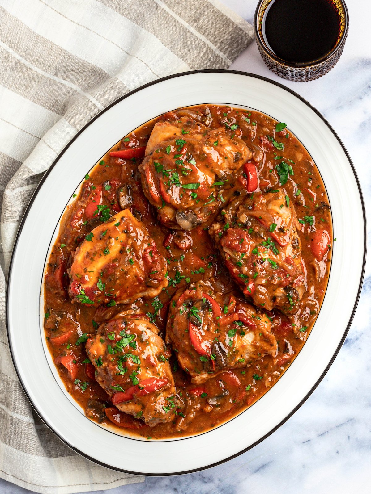 chicken cacciatore on a platter with glass of wine.