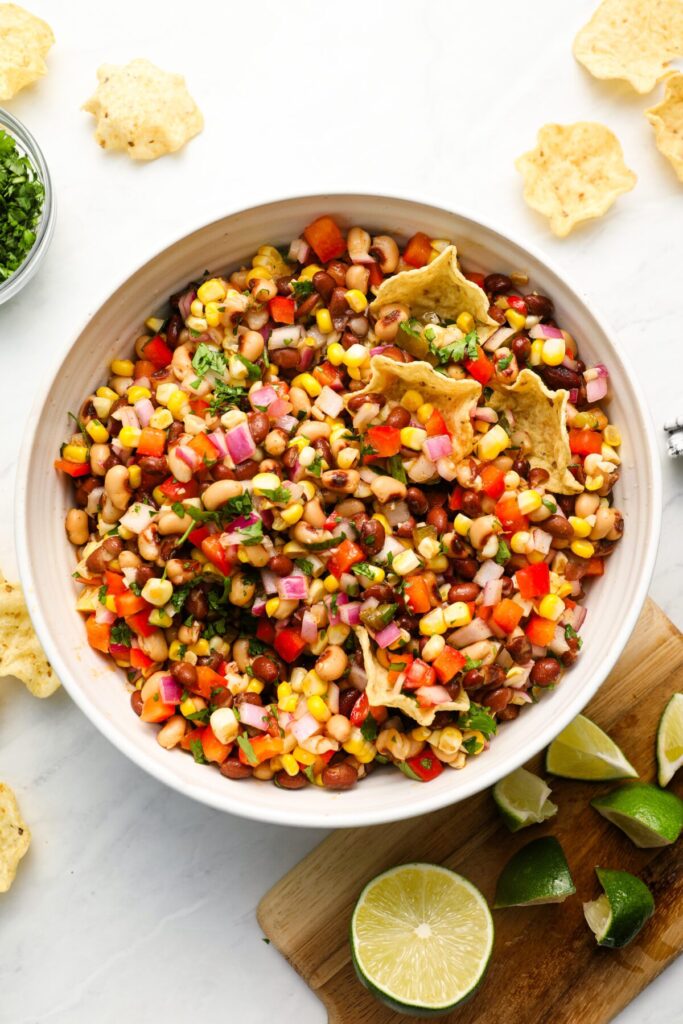 cowboy caviar in serving bowl with chips, cilantro and lime