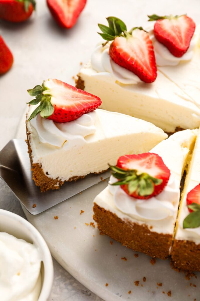 sliced no-bake cheesecake topped with strawberries on platter