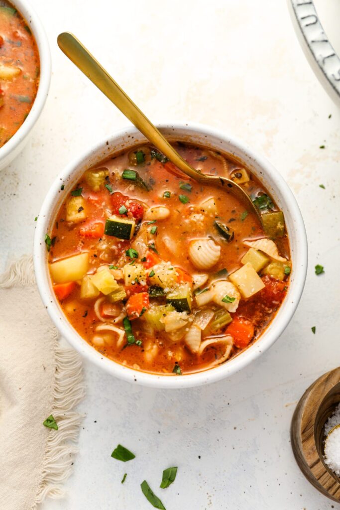 bowl of minestrone soup with spoon and cloth napkin