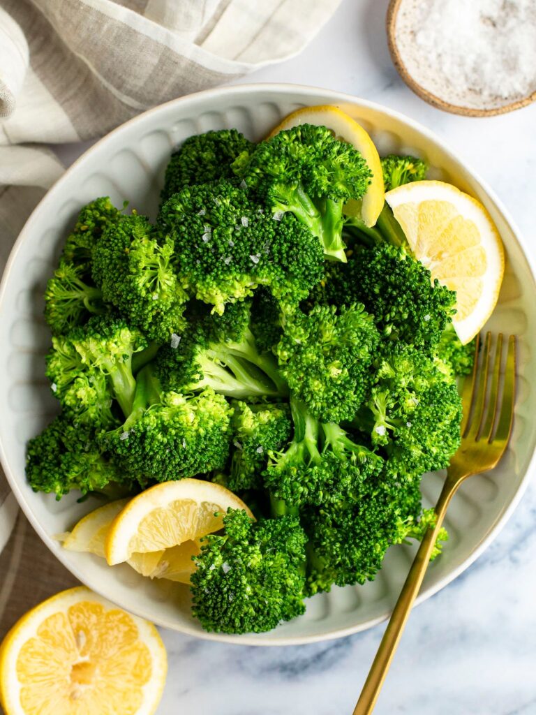 steamed broccoli in bowls with lemon wedges